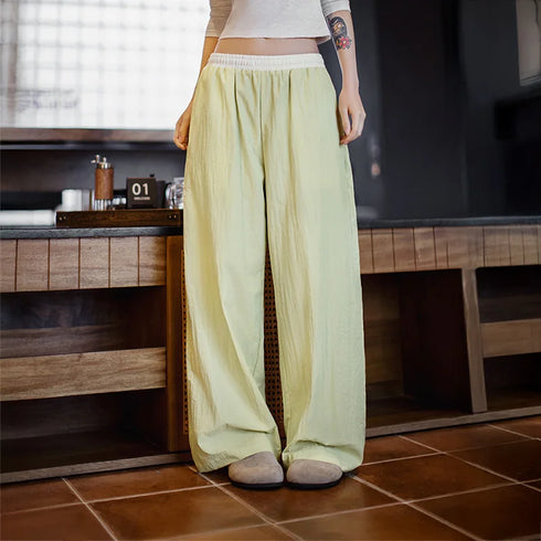 Person wearing light green pants standing in a room with wooden furniture and a tiled floor.
